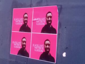 Four identical posters affixed to a wall, depicting George Floyd, and the message, 'Black Lives Matter to Glasgow', white lettering on a pink background, mimicking the style of the city's promotional 'People Make Glasgow' slogan.